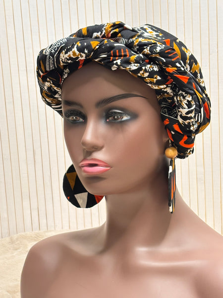 African print head wrap and large disc earrings in a multi colour geometric print with black.