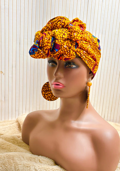 African print head wrap and large disc earrings in a mustard  print with dashes of multi colours.