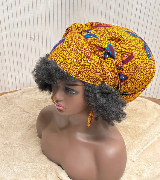 African print head wrap and large disc earrings in a mustard  print with dashes of multi colours.