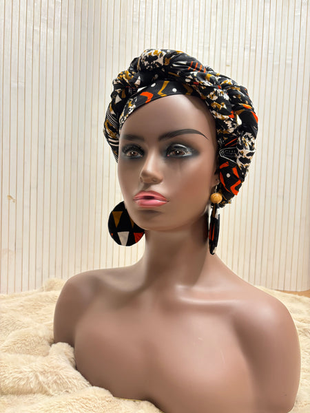 African print head wrap and large disc earrings in a multi colour geometric print with black.