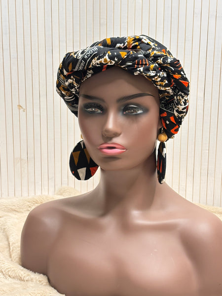 African print head wrap and large disc earrings in a multi colour geometric print with black.