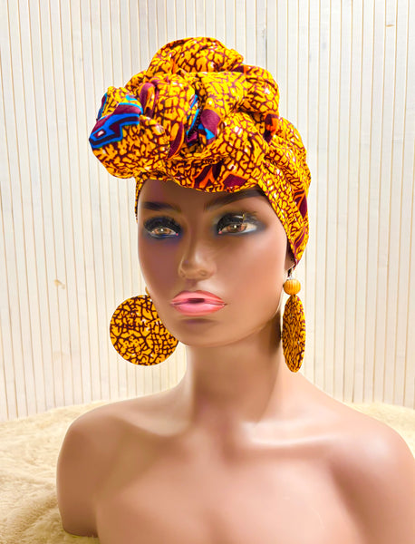 African print head wrap and large disc earrings in a mustard  print with dashes of multi colours.