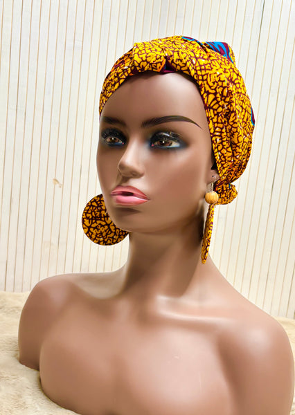 African print head wrap and large disc earrings in a mustard  print with dashes of multi colours.