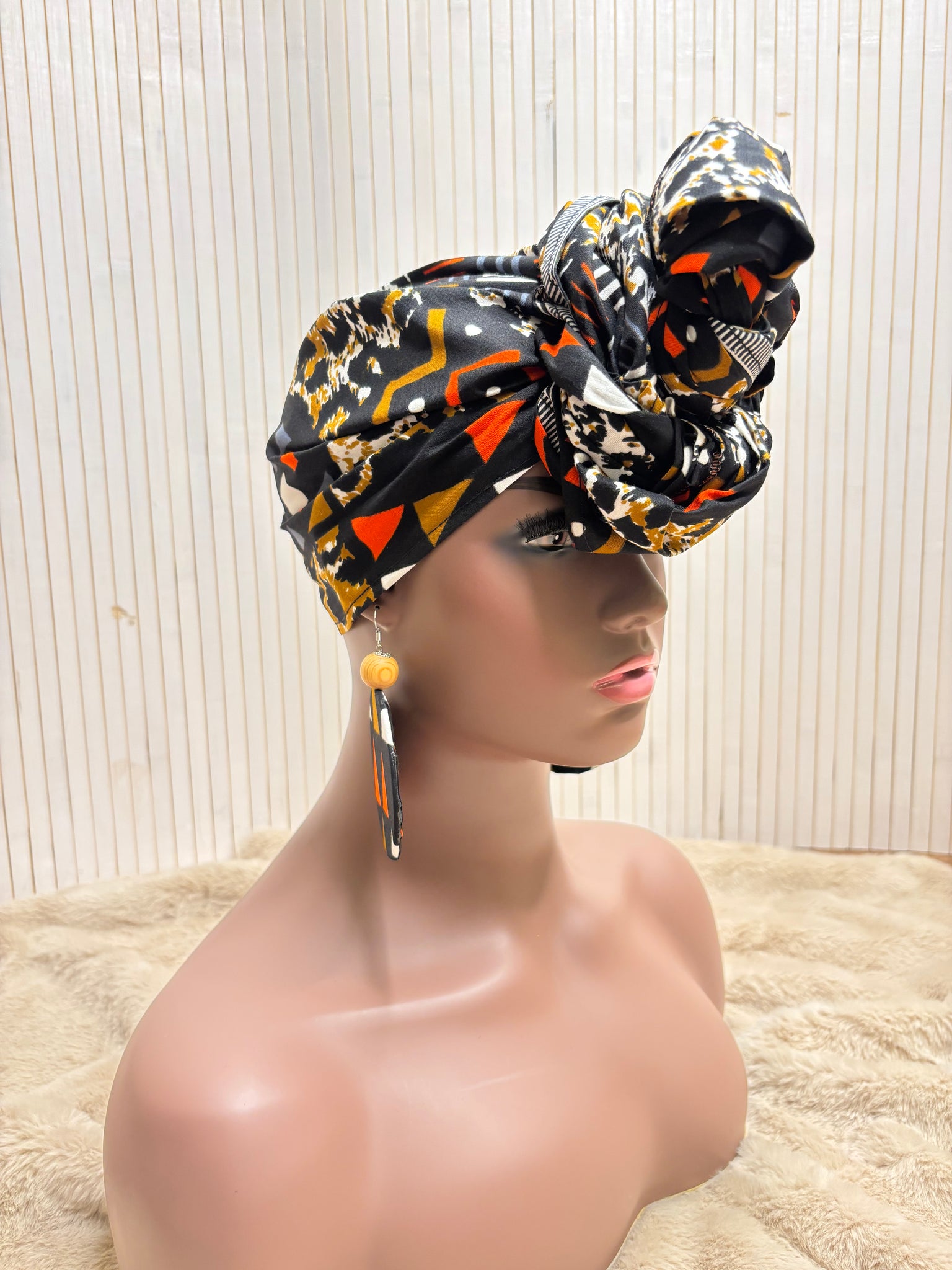 African print head wrap and large disc earrings in a multi colour geometric print with black.