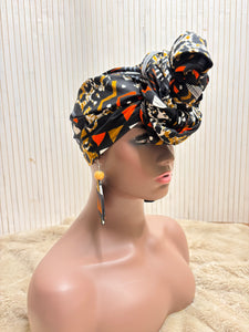 African print head wrap and large disc earrings in a multi colour geometric print with black.