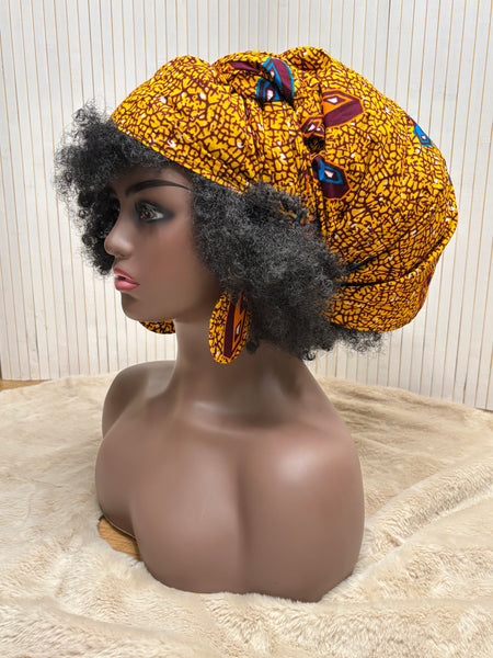 African print head wrap and large disc earrings in a mustard  print with dashes of multi colours.