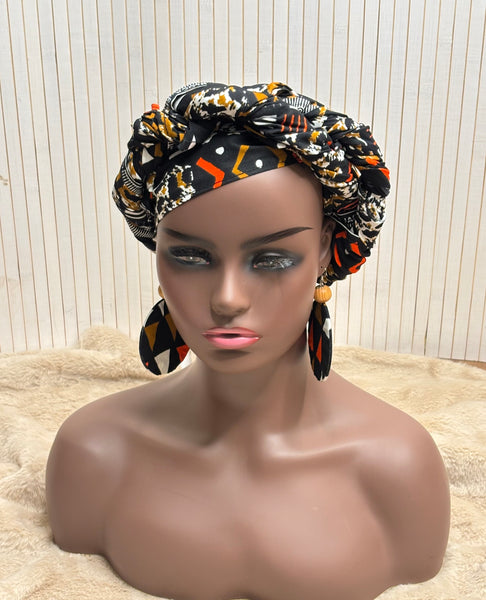 African print head wrap and large disc earrings in a multi colour geometric print with black.