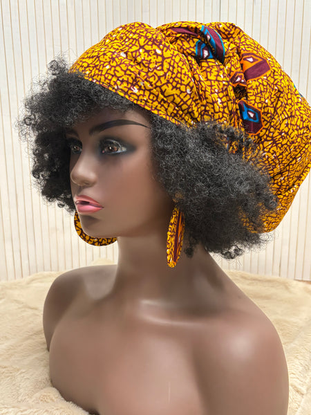 African print head wrap and large disc earrings in a mustard  print with dashes of multi colours.