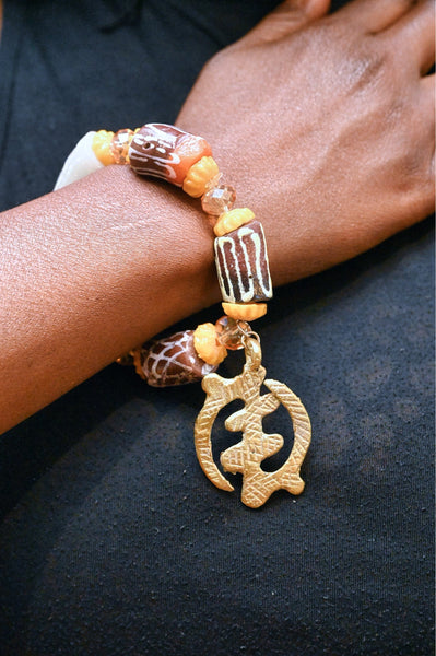 Stretch bracelet with traditional beads and Adinkra pendant.